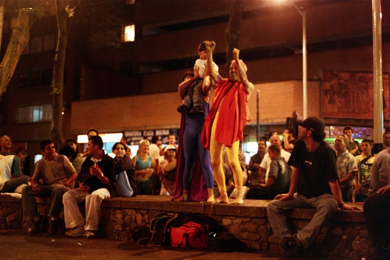 Two actors lift a child in the air infront of a happy crowd.