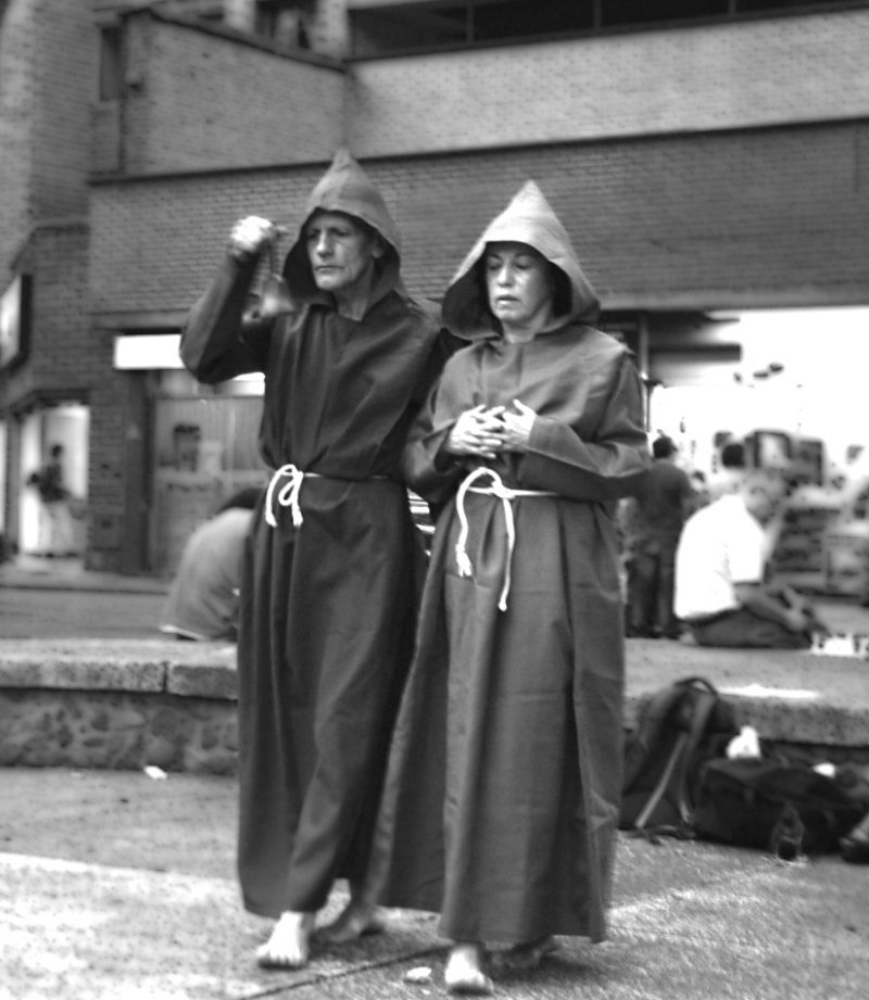 Two performers dressed as monks walking through the street.