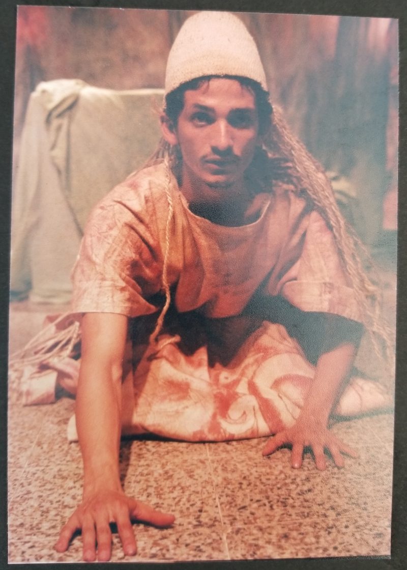 Close-up dramatic shot of an actor sitting on the ground reaching out with his hands.