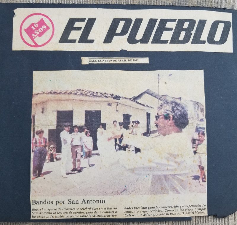 Article image with a man holding a piece of paper up to viewers on a sidewalk.