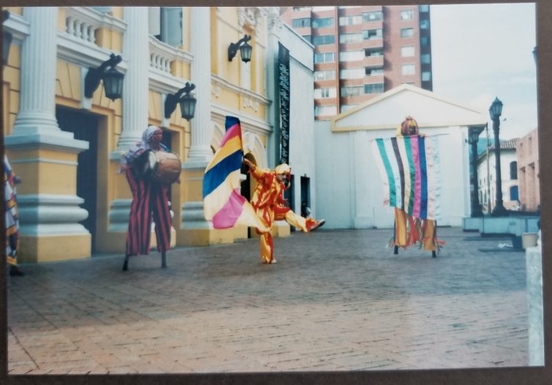 Three street performs dressed in bright colors, two of them with stilts on.