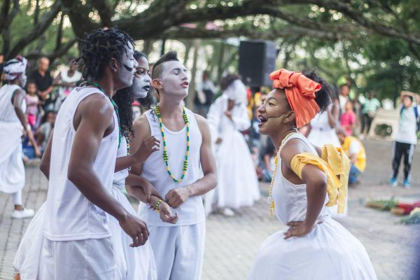 Four performers in white standing in a circle.